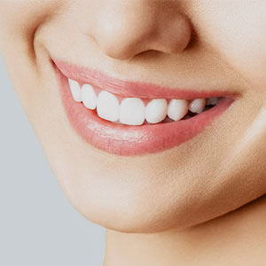 The image features a close-up of a person s face, focusing on their smiling mouth and teeth.